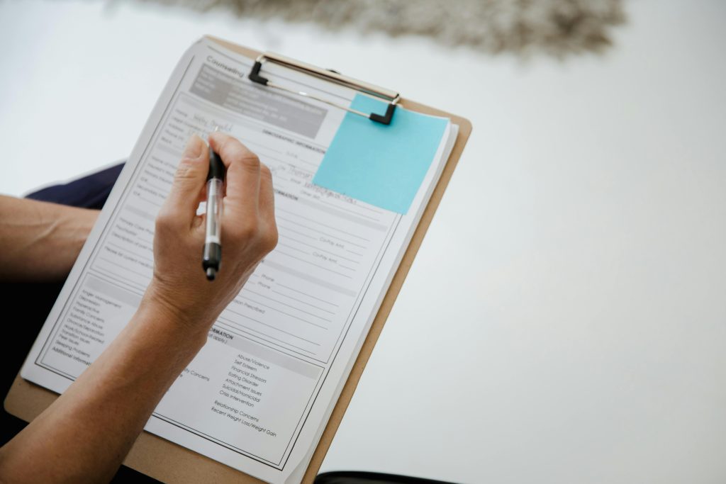 A person writes on a document using a clipboard indoors.